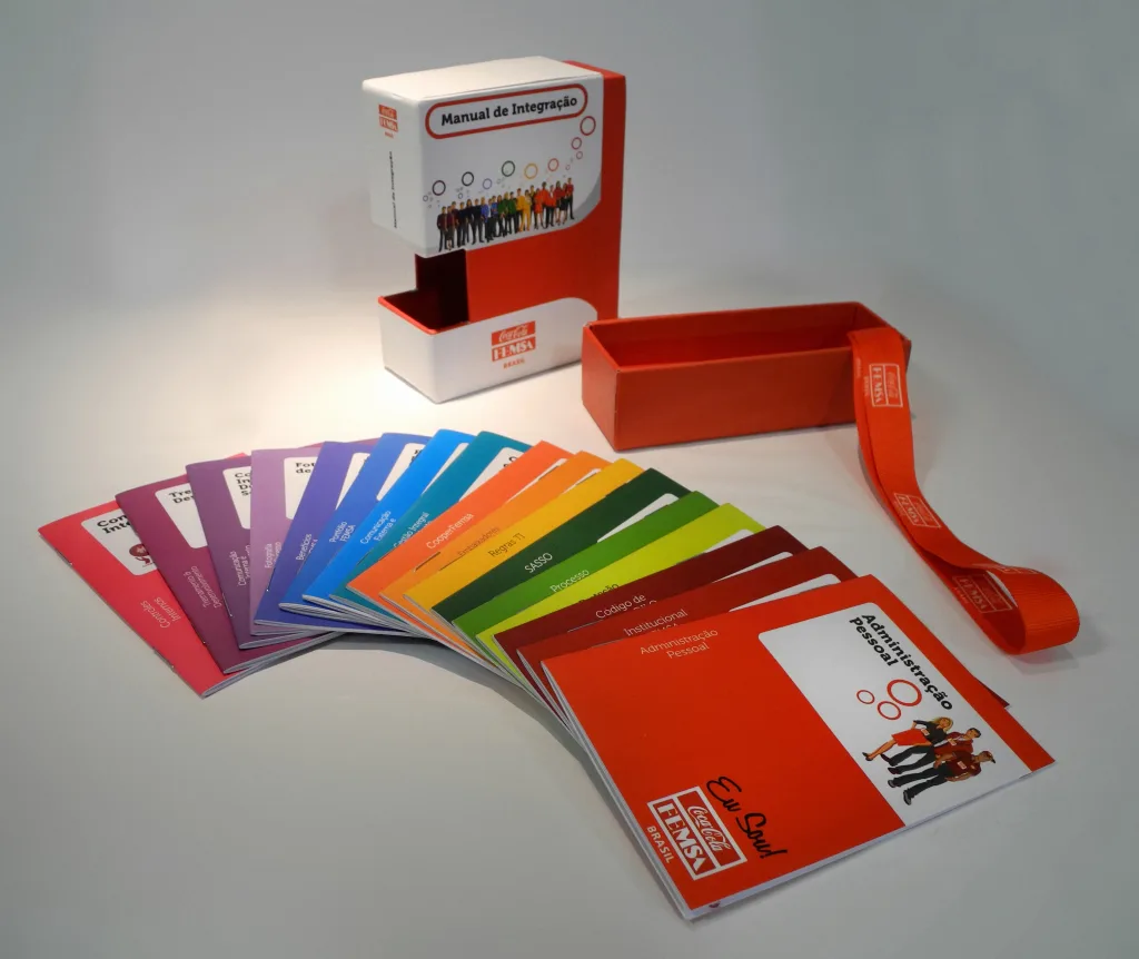 Caixa Manual de Integração da Coca-Cola FEMSA com leque de manuais coloridos por tema