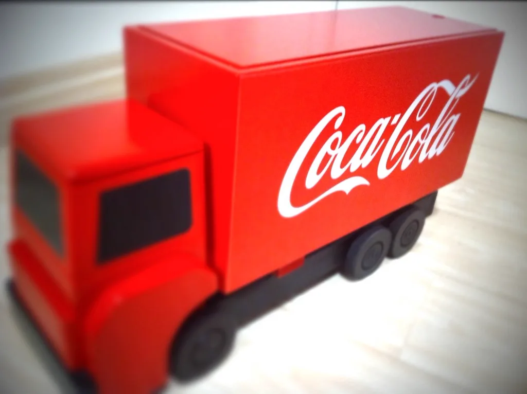 Caminhão de brinquedo vermelho com logo da Coca-Cola, peça do jogo de integração de logística